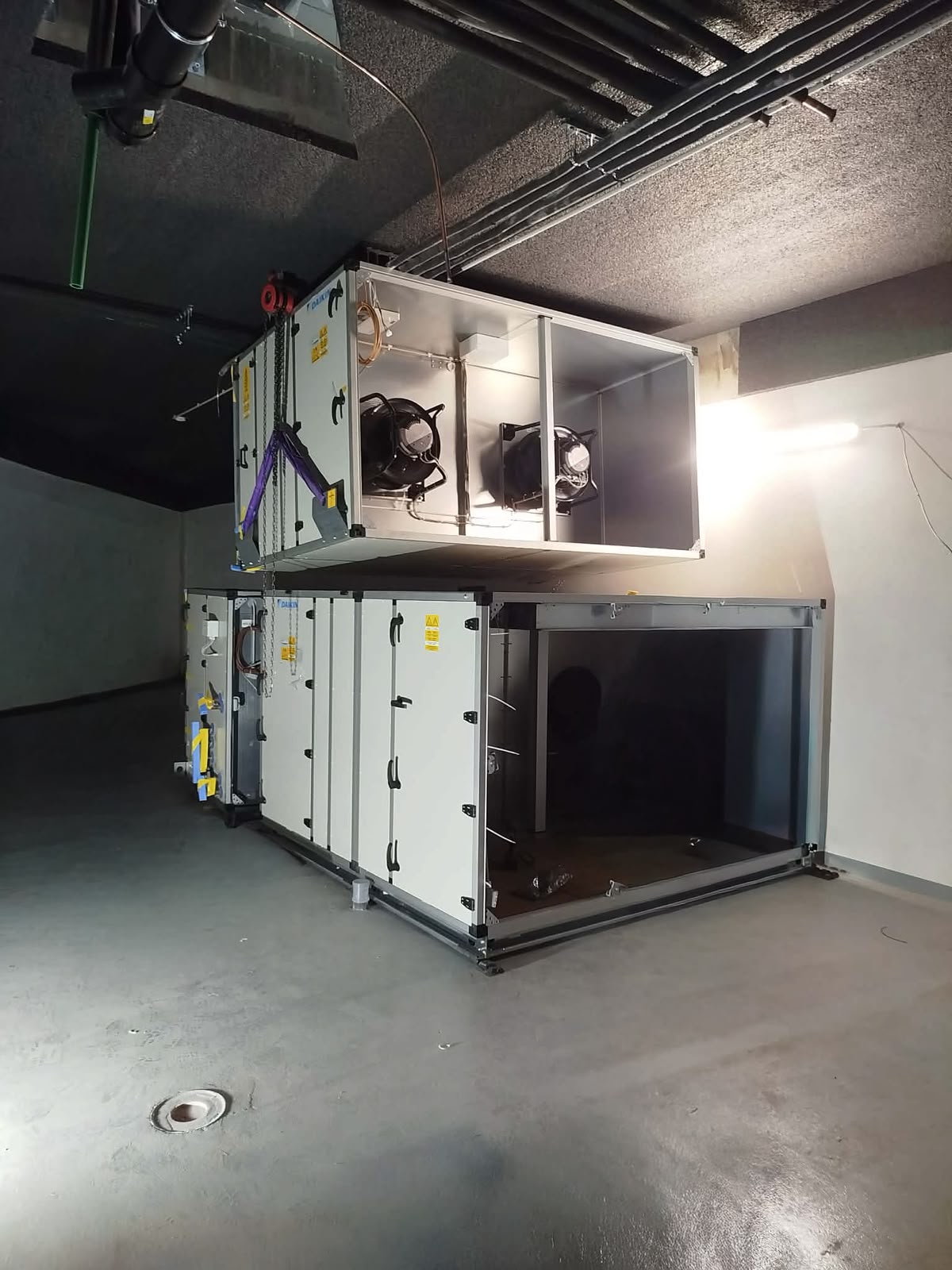 Daikin légkezelő egységek kétszintes elrendezésben gépházban, felül két ventilátormodullal és alul fekete zárakkal ellátott szervízajtós szekrénnyel